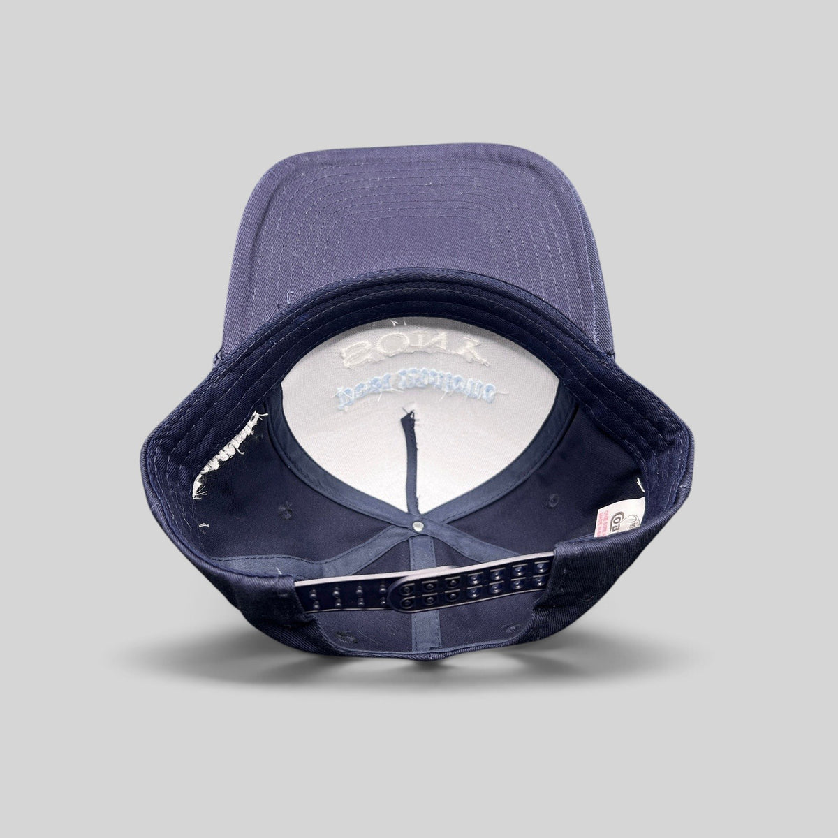 Raree Finds navy blue snapback hat with interior view showing structured foam front and adjustable plastic closure