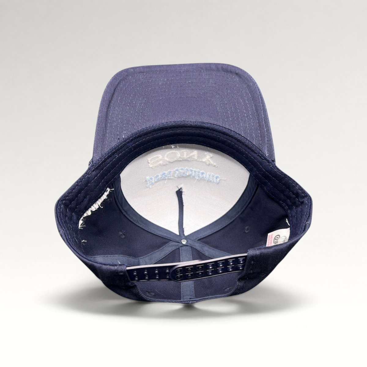 Raree Finds navy blue snapback hat with interior view showing structured foam front and adjustable plastic closure