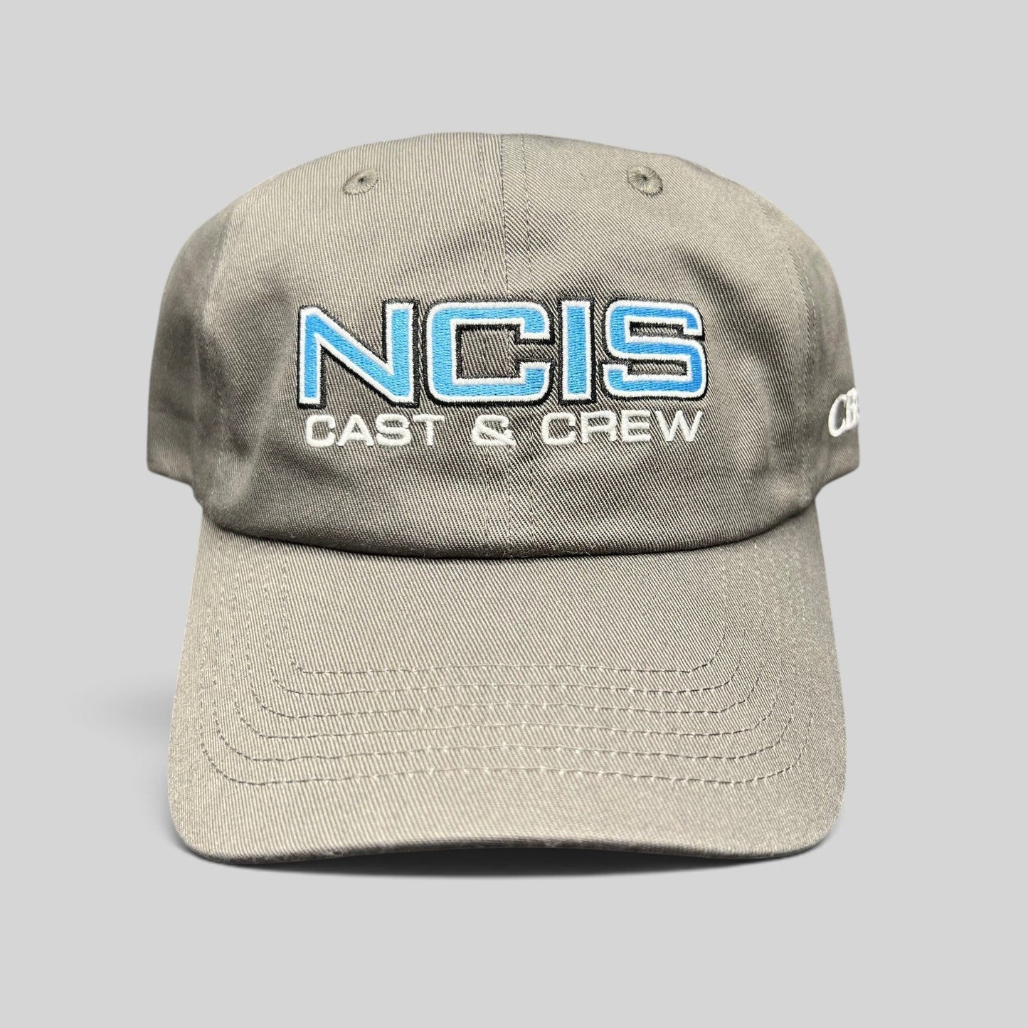 Raree Finds gray NCIS Cast & Crew strapback hat with blue and white embroidered logo on a curved bill cap