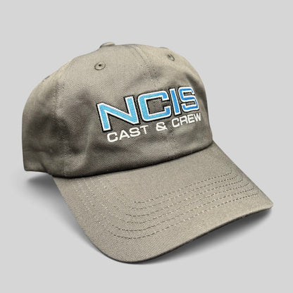 Raree Finds gray NCIS Cast & Crew strapback hat with blue and white embroidered logo on a curved bill cap.