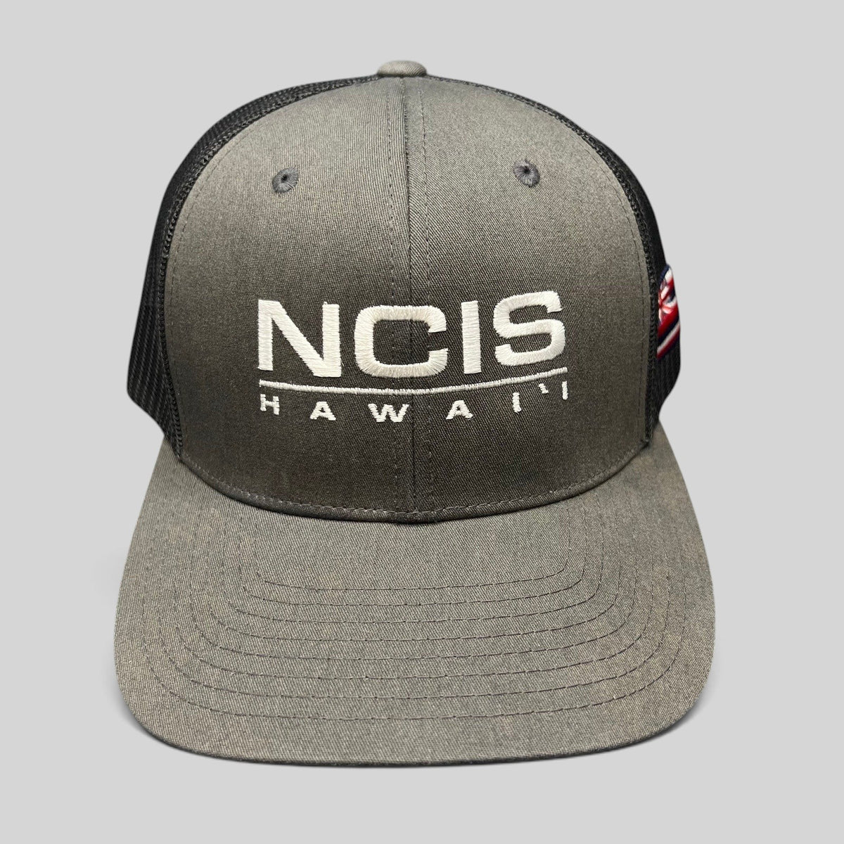 Raree Finds NCIS Hawaii film crew trucker hat with gray structured crown, black mesh back, and white front embroidery.