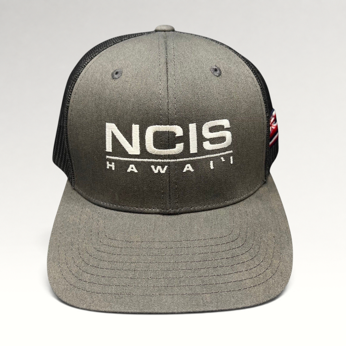 Raree Finds NCIS Hawaii film crew trucker hat with gray structured crown, black mesh back, and white front embroidery.
