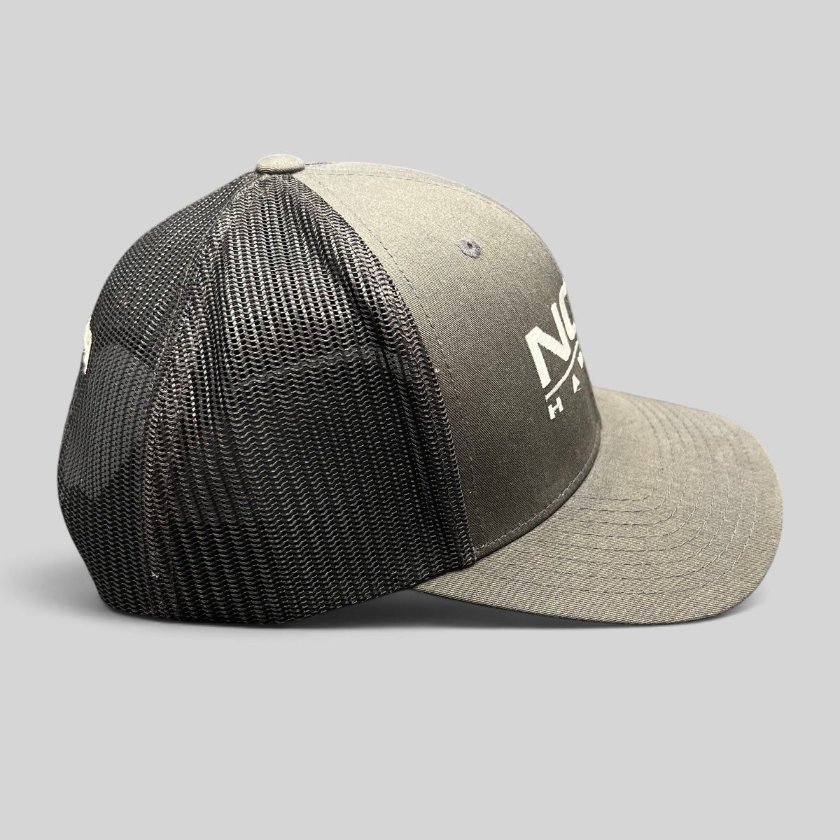 Raree Finds NCIS Hawaii Yupoong Classics trucker hat with gray structured crown, black mesh back, and white logo.