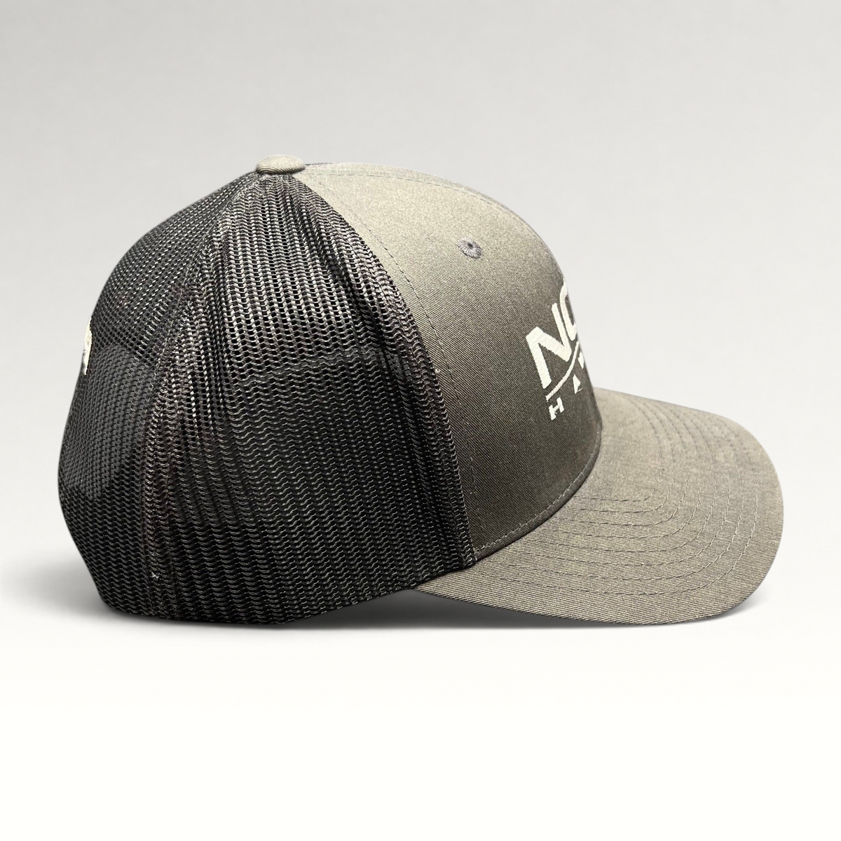 Raree Finds NCIS Hawaii Yupoong Classics trucker hat with gray structured crown, black mesh back, and white logo.