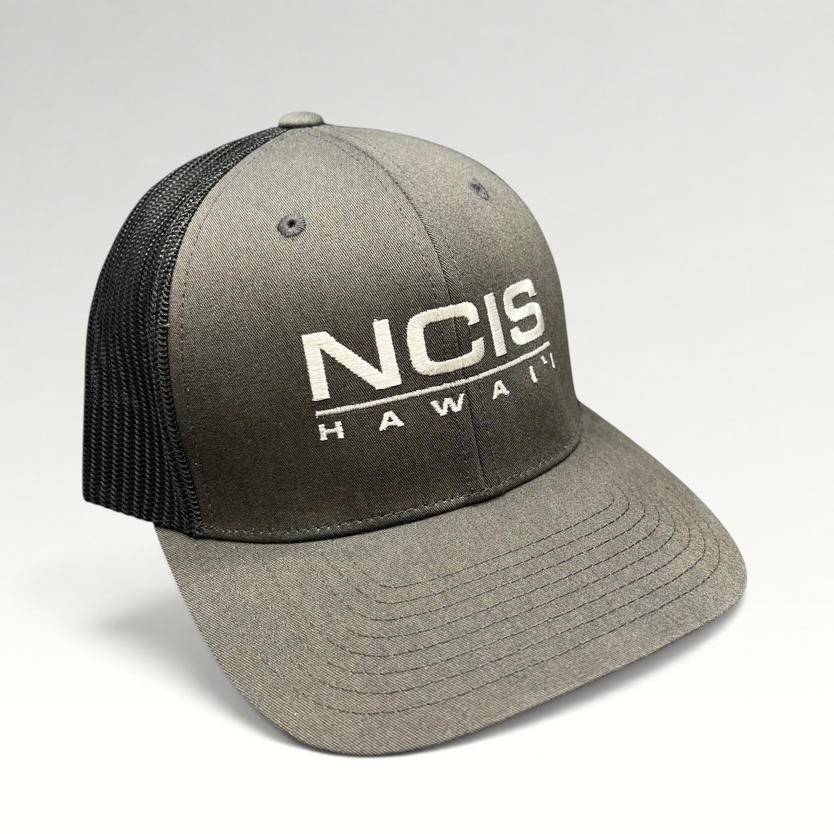Raree Finds NCIS Hawaii film crew trucker hat with gray structured crown, black mesh back, and white front embroidery.