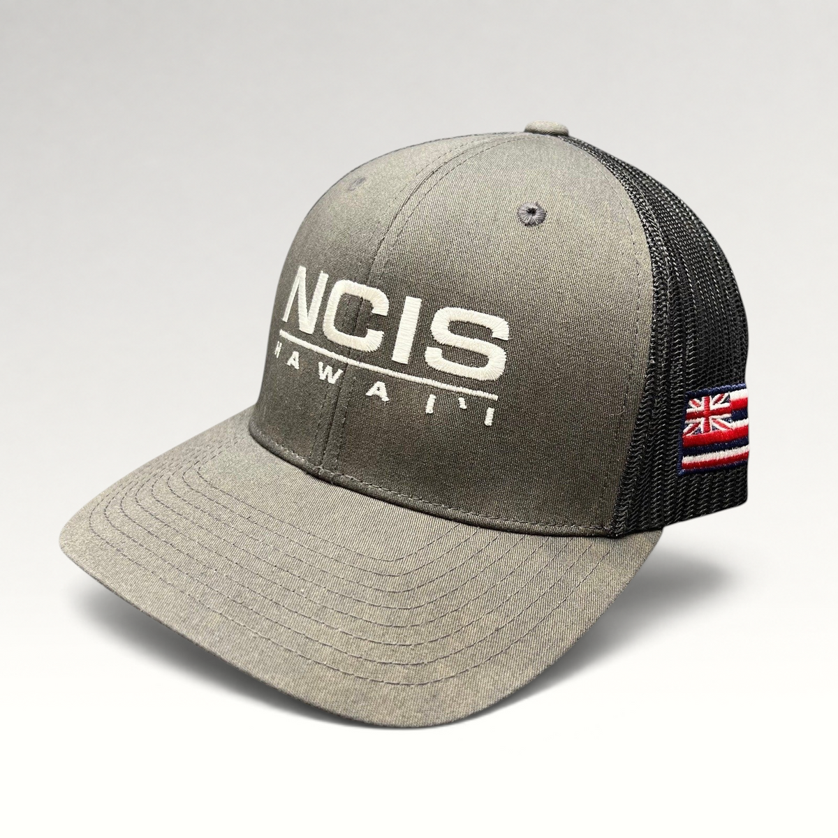 Raree Finds NCIS Hawaii trucker hat with gray structured crown, black mesh back, and white embroidered front logo.