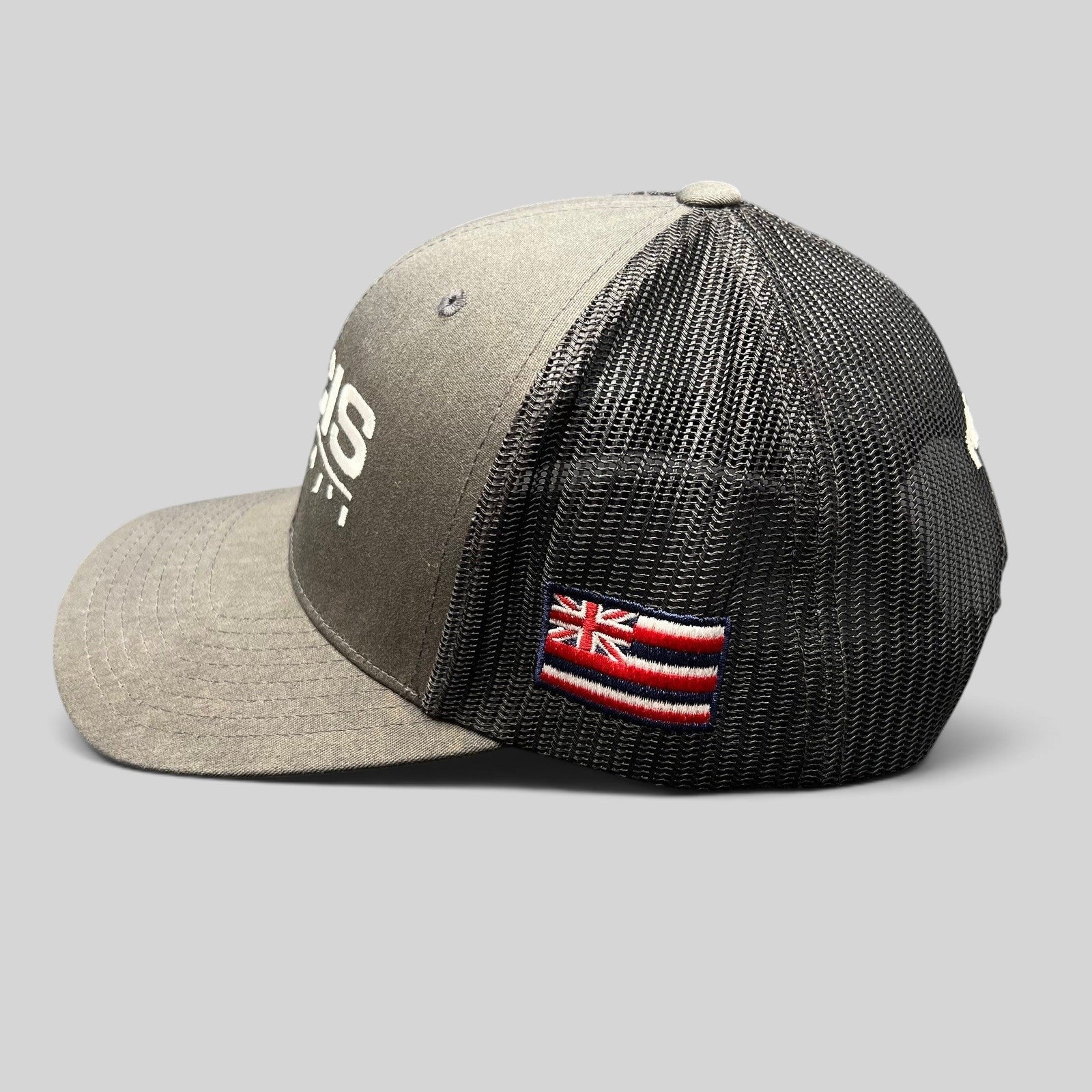 Raree Finds NCIS Hawaii trucker hat in gray and black with white embroidery and a side Hawaii state flag patch
