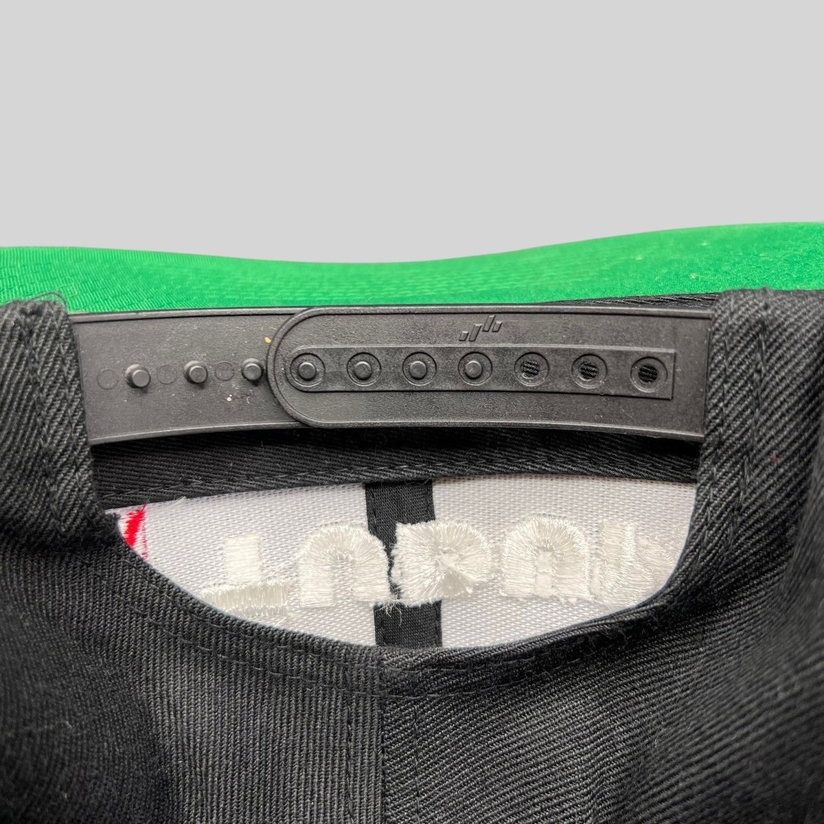 Raree Finds Netflix Tudum snapback hat showing the adjustable black plastic snap closure and green undervisor detail.