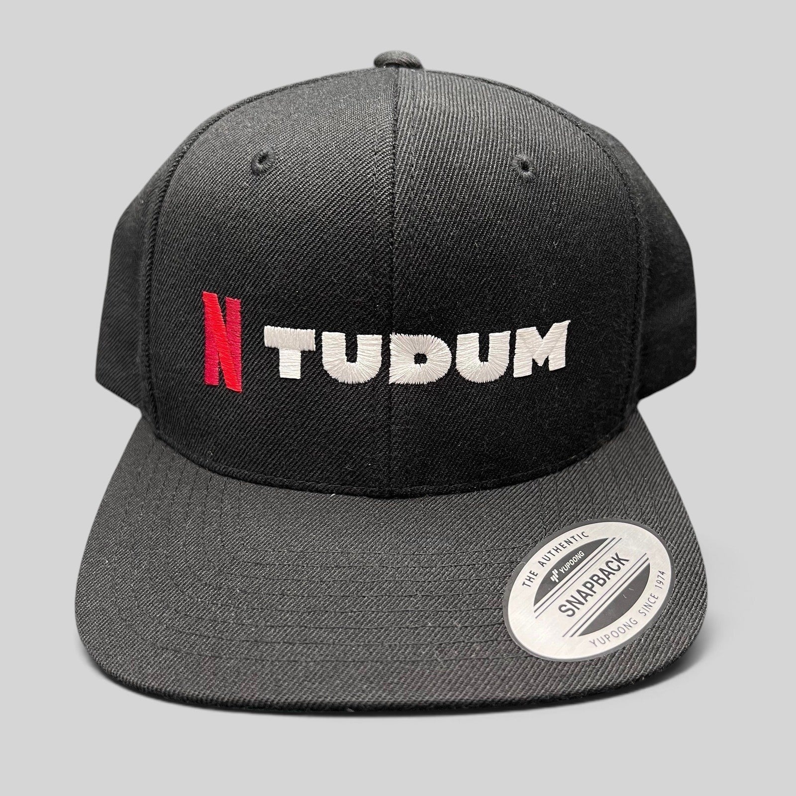Raree Finds Netflix Tudum promotional black snapback hat with red N and white TUDUM embroidery on a Yupoong base.