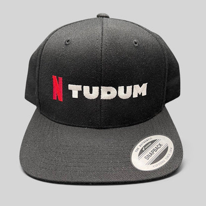 Raree Finds Netflix Tudum promotional black snapback hat with red N and white TUDUM embroidery on a Yupoong base.