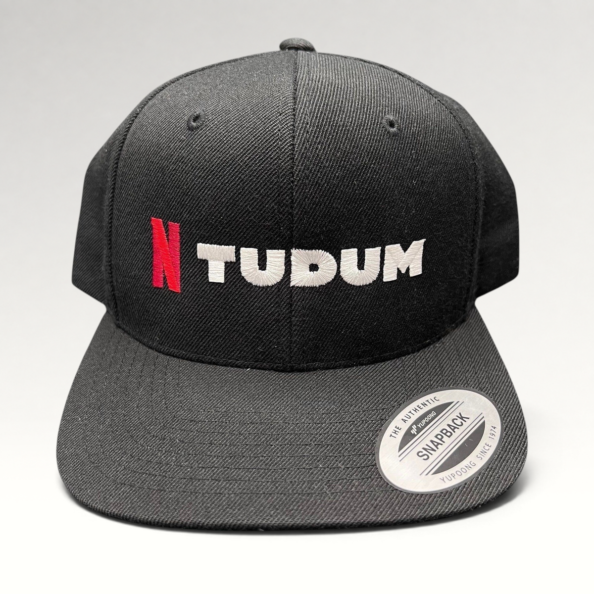 Raree Finds Netflix Tudum promotional black snapback hat with red N and white TUDUM embroidery on a Yupoong base.