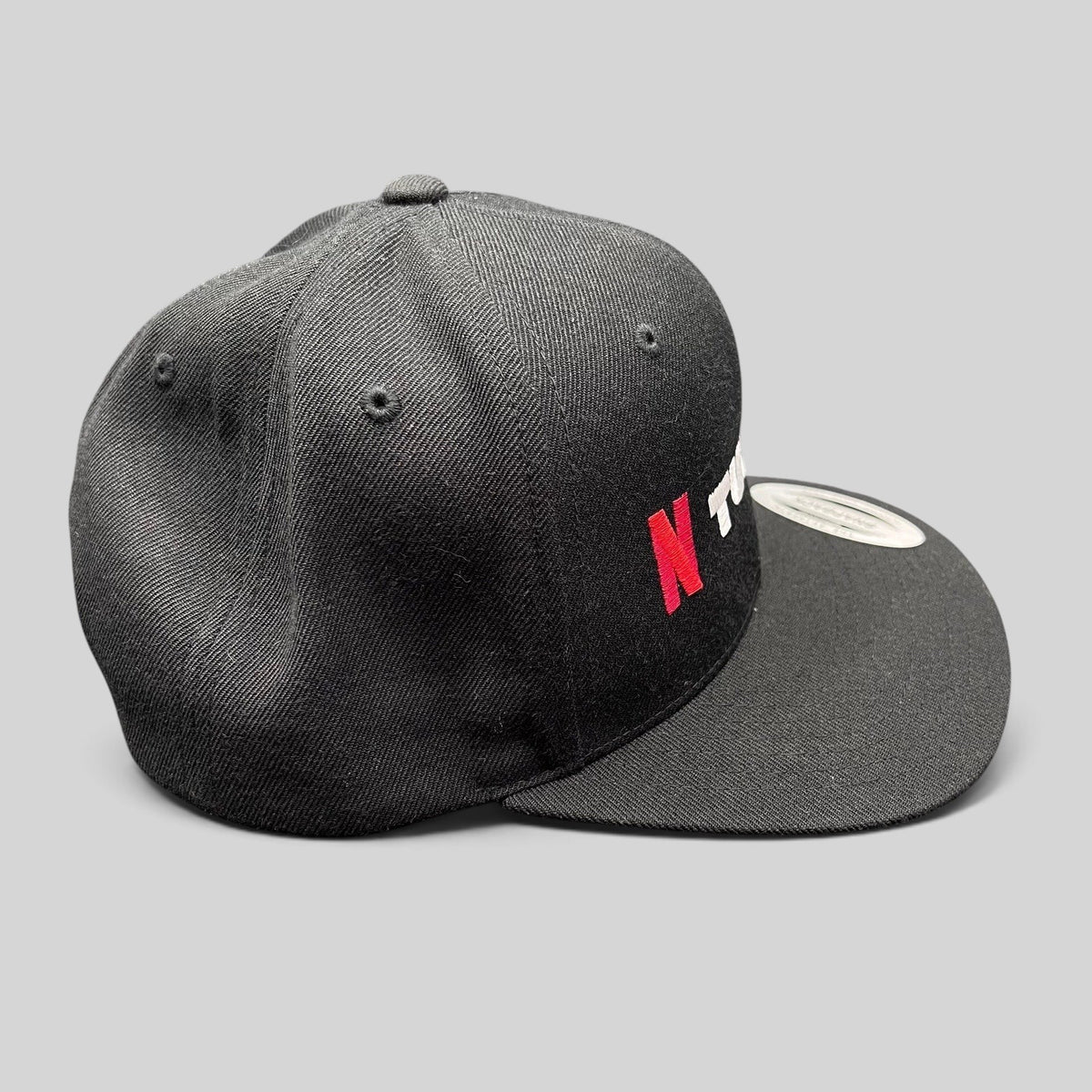 Raree Finds Netflix Tudum promotional snapback hat in black with red and white embroidery and a flat brim.