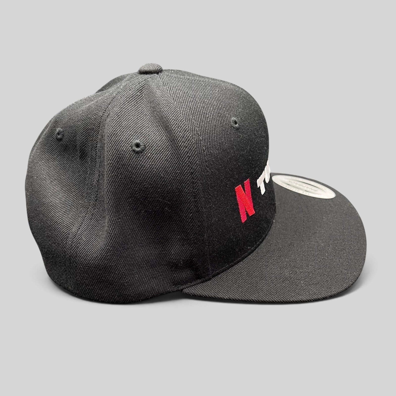 Raree Finds Netflix Tudum promotional snapback hat in black with red and white embroidery and a flat brim.