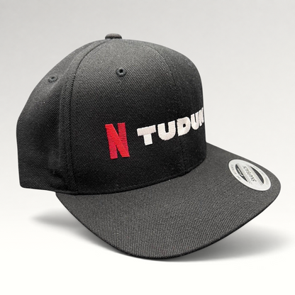 Raree Finds Netflix Tudum black snapback hat with red N logo and white TUDUM embroidery on a Yupoong classic cap.