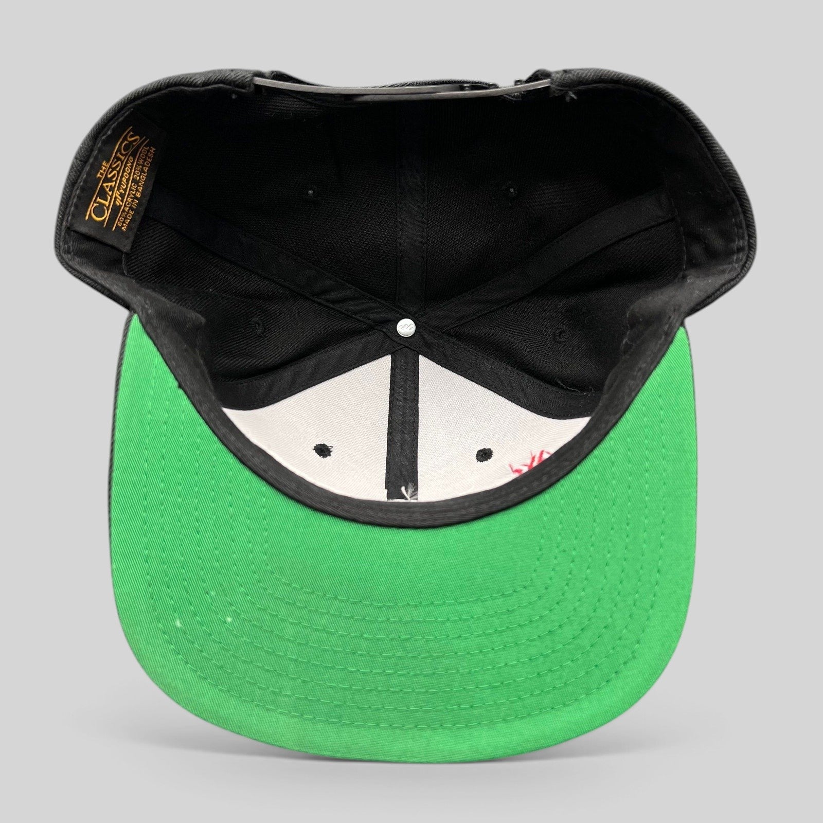 Raree Finds Netflix Tudum snapback hat showing the interior construction, green undervisor, and Yupoong Classics label.