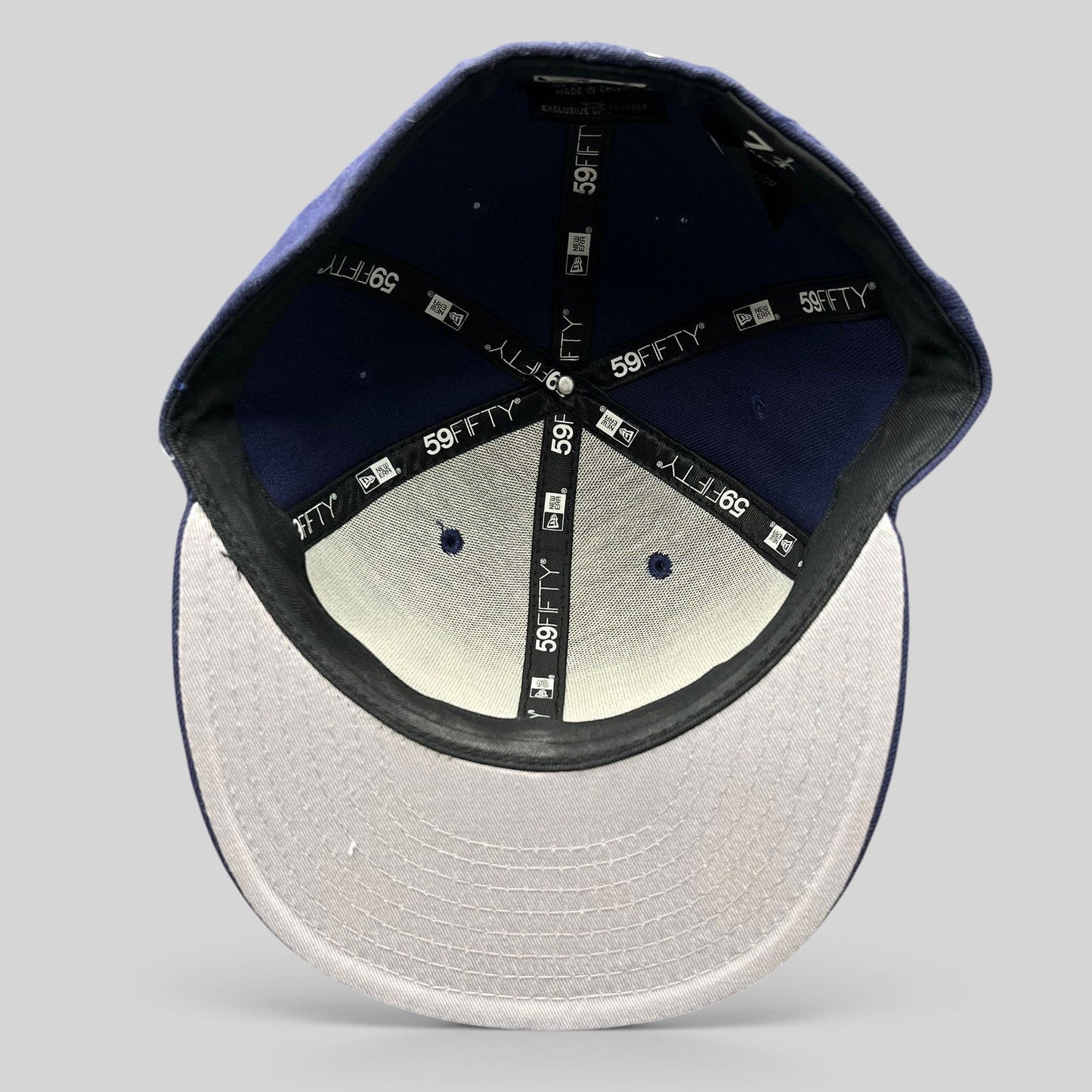 Interior view of a Raree Finds New Era 59FIFTY navy fitted hat showing branded taping and size 7 1/4 label.