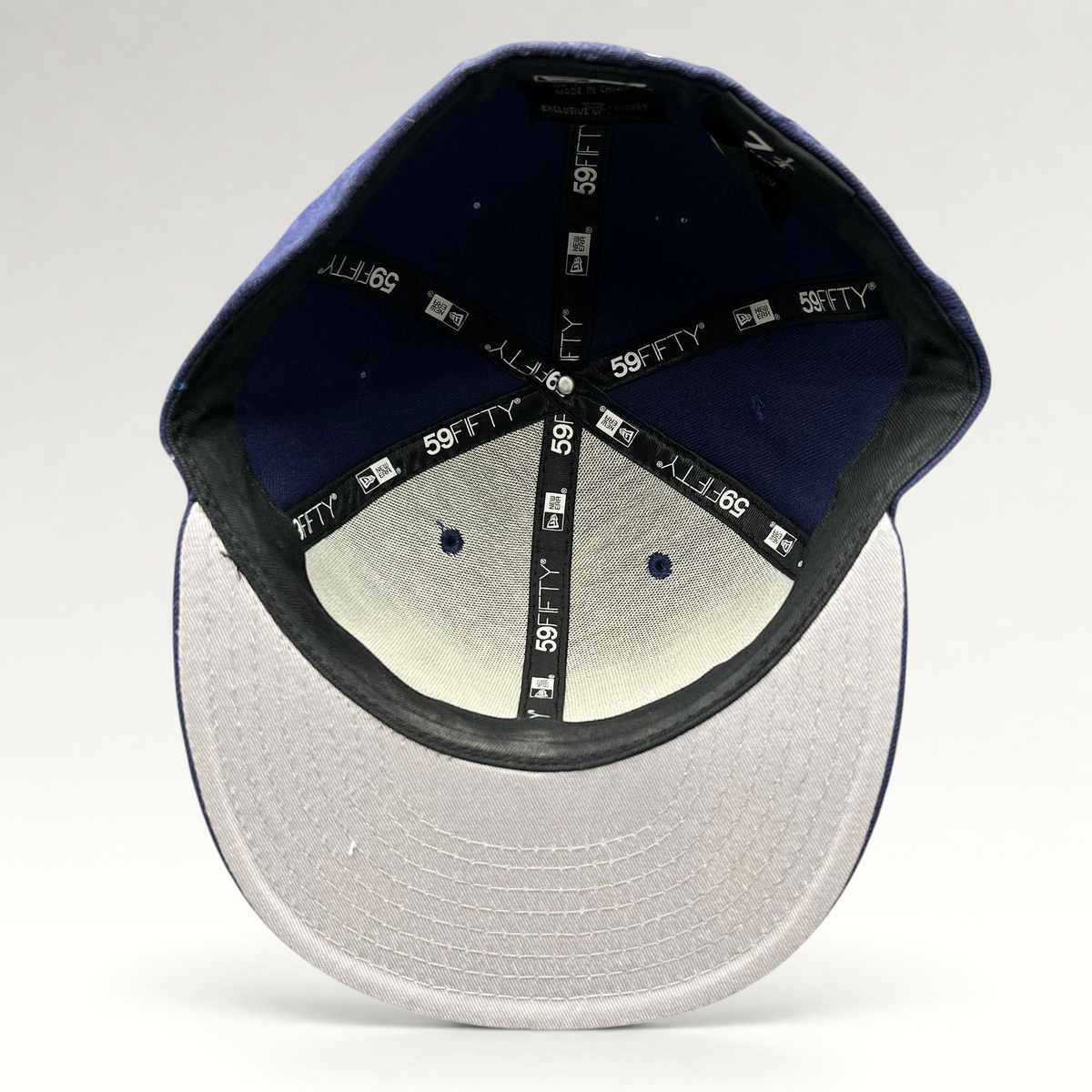 Interior view of a Raree Finds New Era 59FIFTY navy fitted hat showing branded taping and size 7 1/4 label.