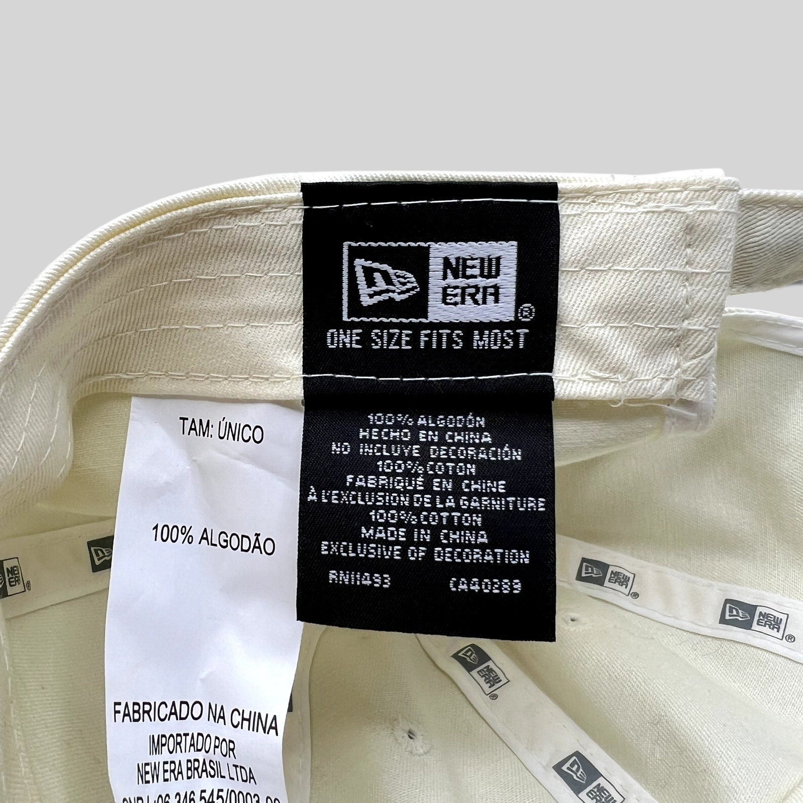 Raree Finds cream New Era strapback hat interior label showing 100% cotton material and manufacturing details