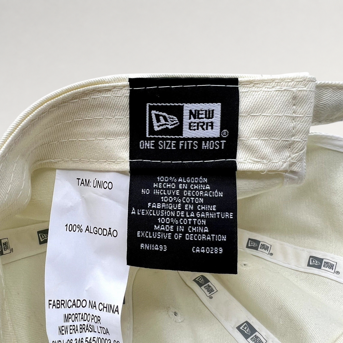 Raree Finds cream New Era strapback hat interior label showing 100% cotton material and manufacturing details