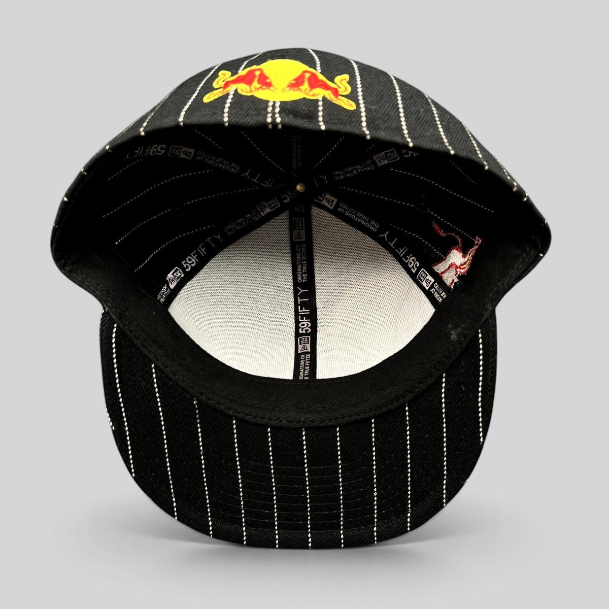 Raree Finds New Era 59FIFTY fitted hat in black with white pinstripes and Red Bull embroidery, interior view.