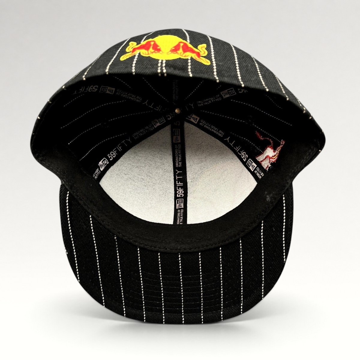 Raree Finds New Era 59FIFTY fitted hat in black with white pinstripes and Red Bull embroidery, interior view.