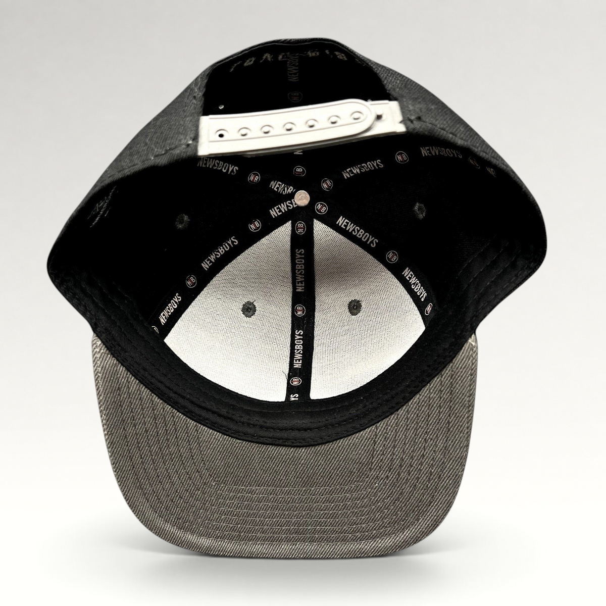 Raree Finds Newsboys Love Riot snapback hat interior showing branded taping, adjustable closure, and gray flat brim.