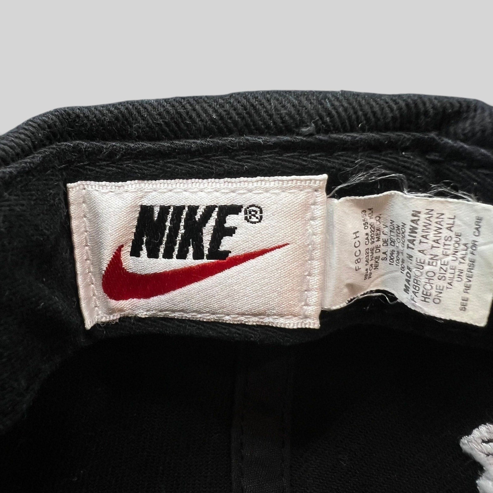 Raree Finds vintage 90s Nike snapback cap interior tag showing brand logo and manufacturing details on black cotton
