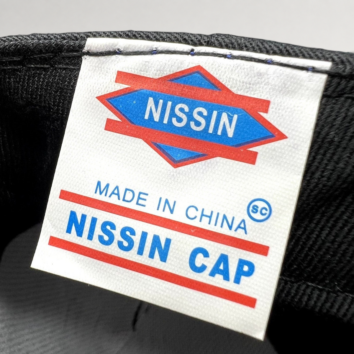 Raree Finds vintage Nissin Cap clothing label inside a black cotton strapback hat for Samy’s CinemaWorks