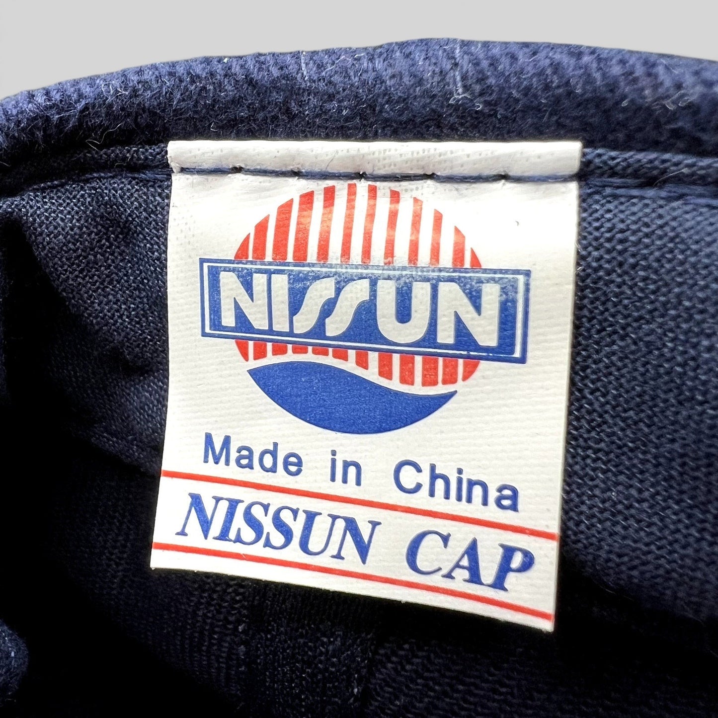 Raree Finds vintage Nissun cap interior fabric label showing brand logo and Made in China text on navy blue cotton