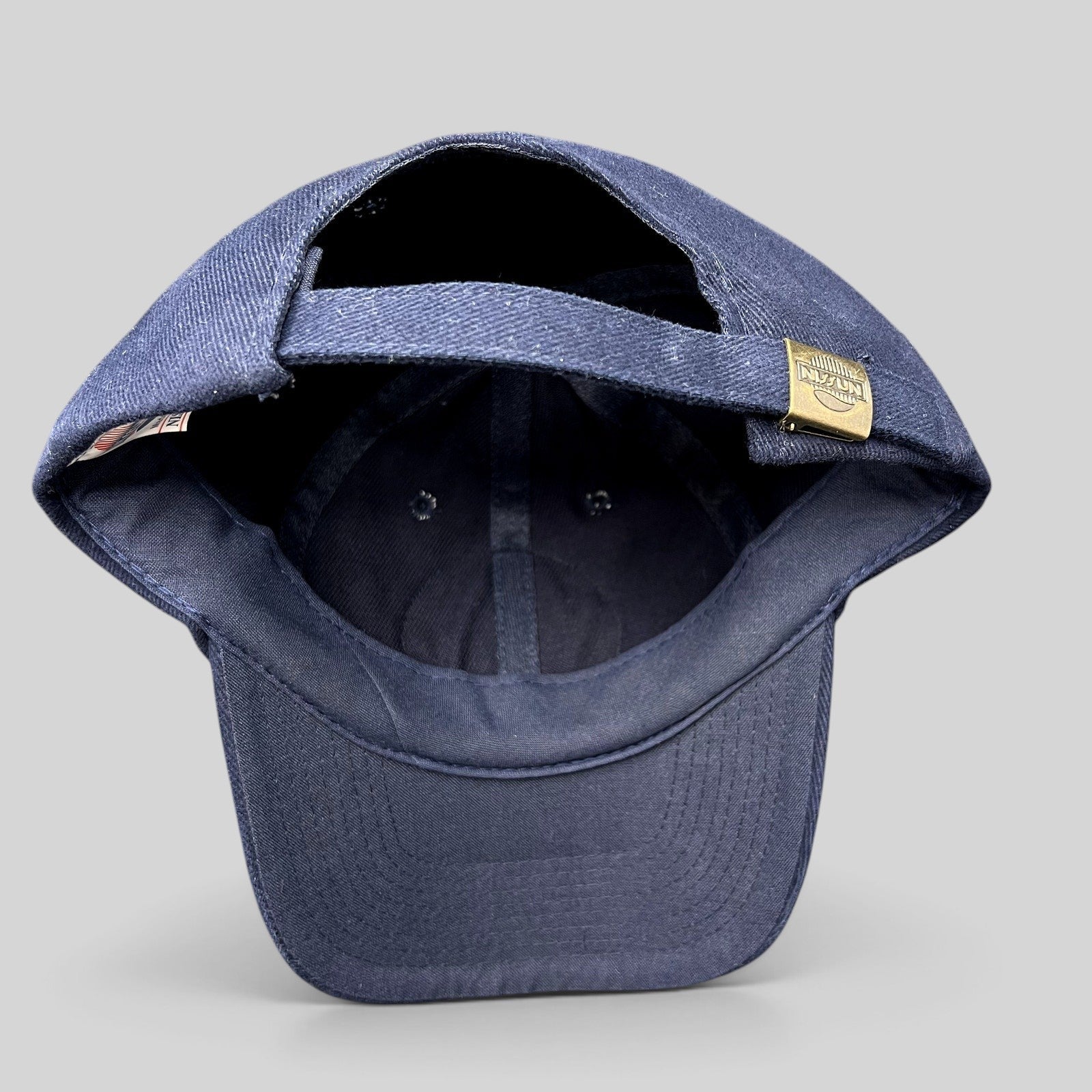 Raree Finds vintage Nissun navy blue cotton strapback hat showing the adjustable metal clasp closure