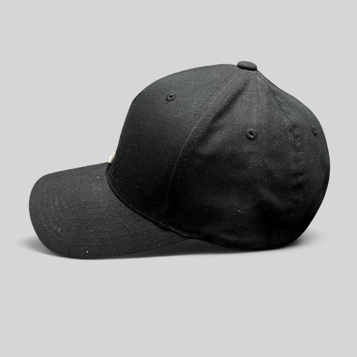 Raree Finds black Nixon Watches Flexfit fitted cap with white embroidered logo, side profile view.