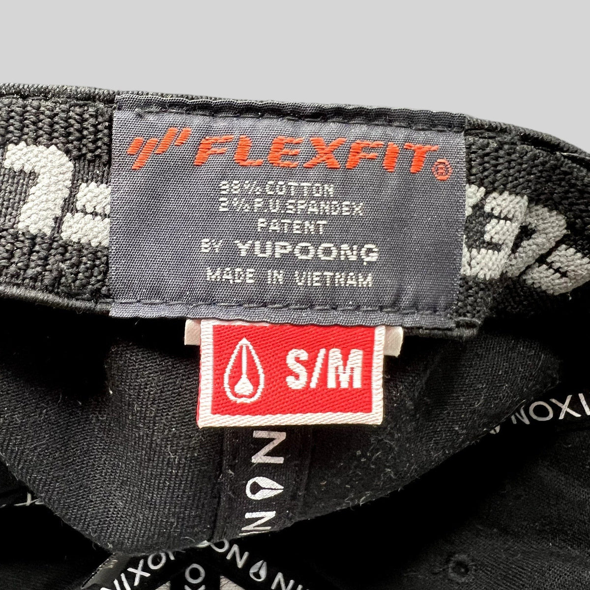 Raree Finds Nixon Watches Flexfit cap interior tag showing size S/M and Yupoong branding on a black cotton blend hat