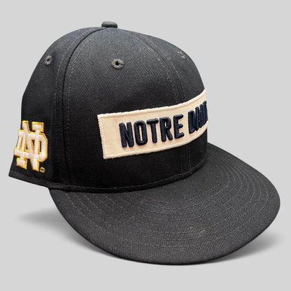 Raree Finds black New Era 9FIFTY snapback hat with cream Notre Dame wordmark patch and side logo embroidery