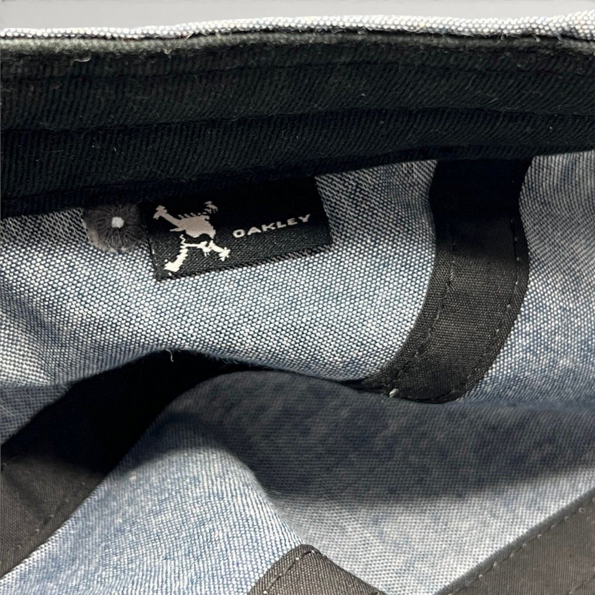 Raree Finds Oakley 5-panel cap interior showing the skull logo brand tag on light denim chambray fabric