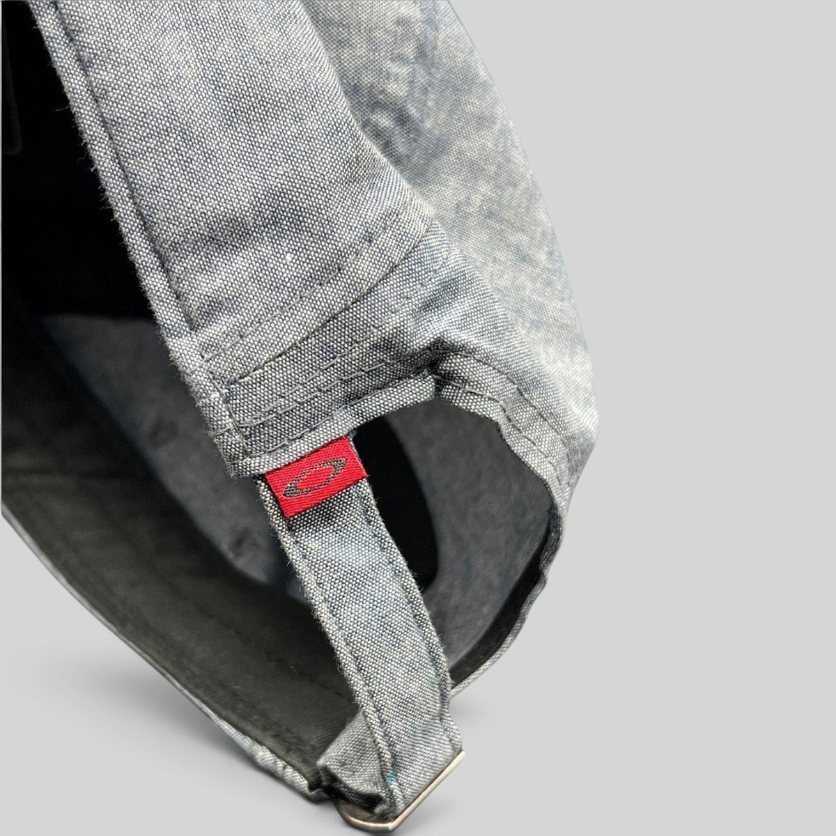 Raree Finds Oakley 5-panel cap in light denim chambray with red skull logo tag on the adjustable metal buckle strap