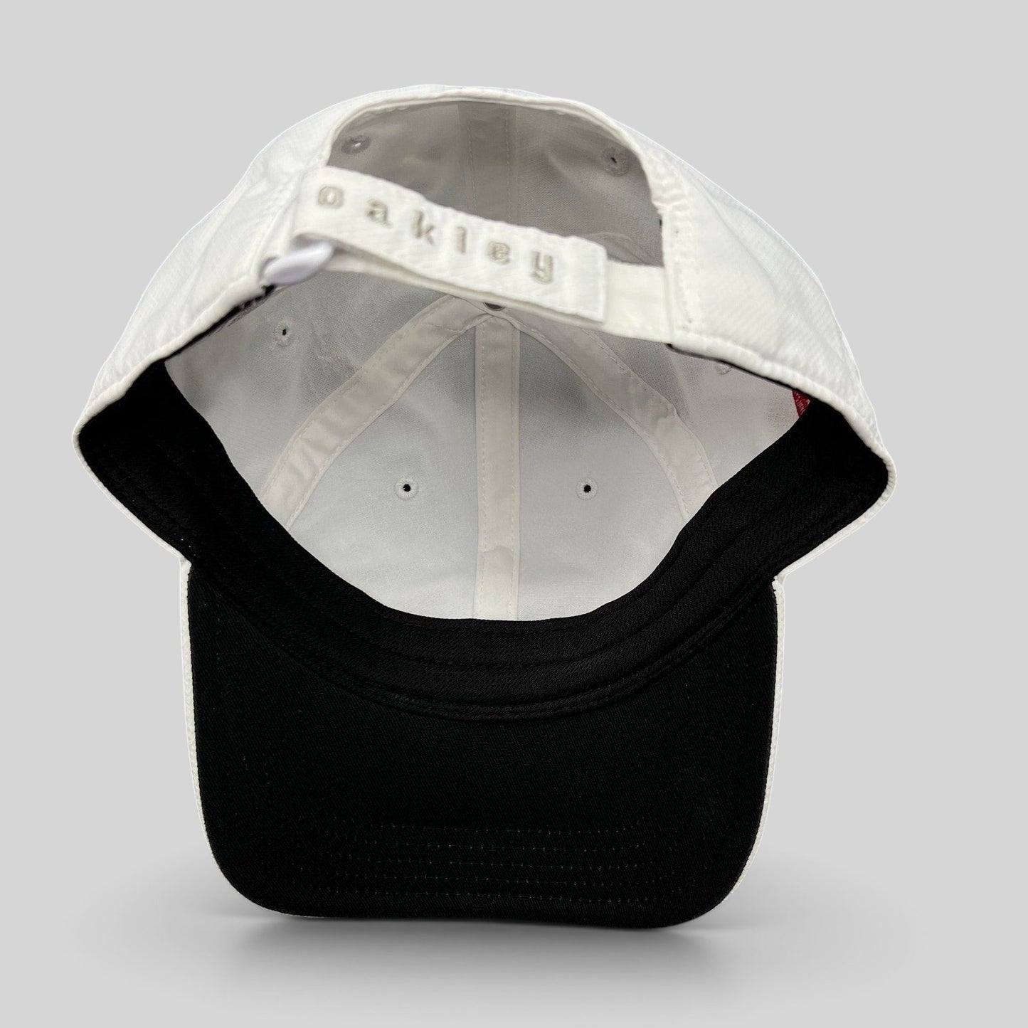 Raree Finds Oakley Hydrolix white performance cap featuring a black brim and adjustable Velcro strap with logo detail.