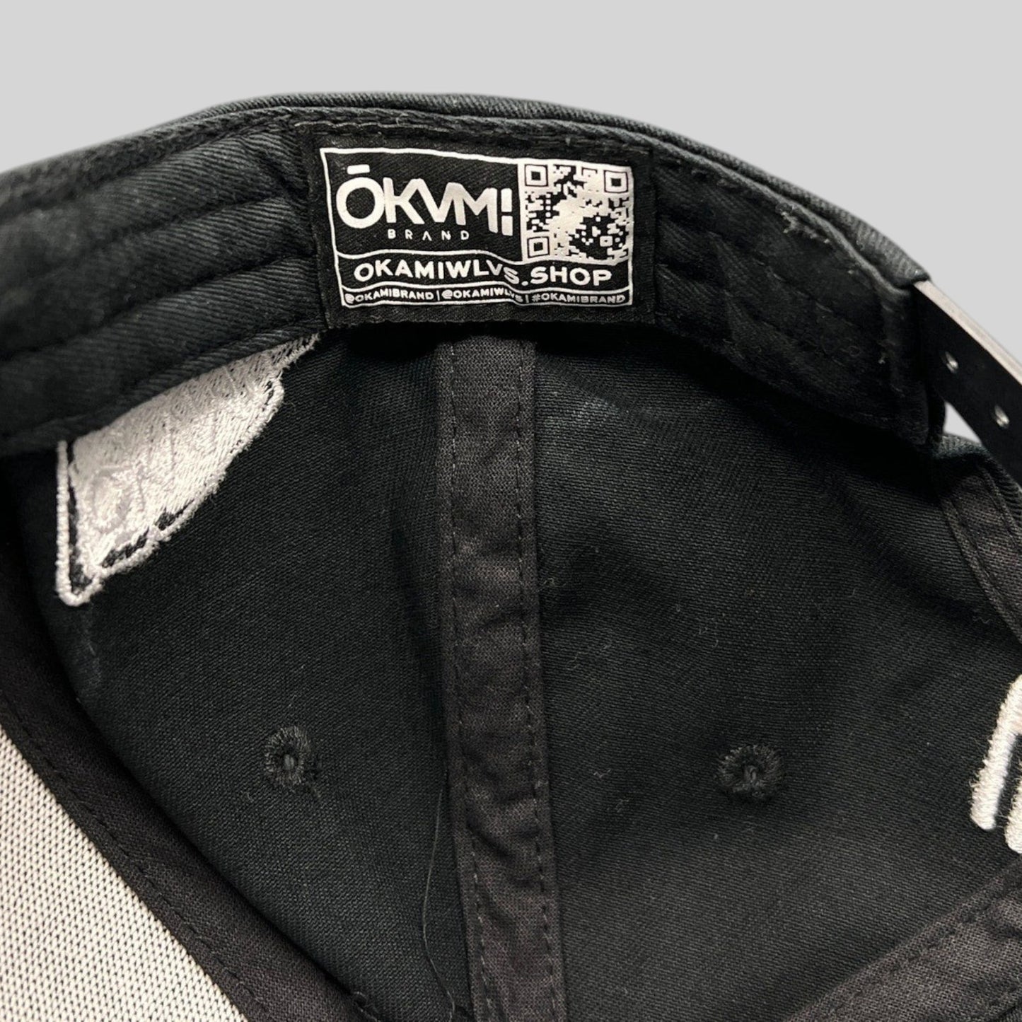 Raree Finds black Okami Brand strapback hat interior showing authentic branded label with QR code and taping