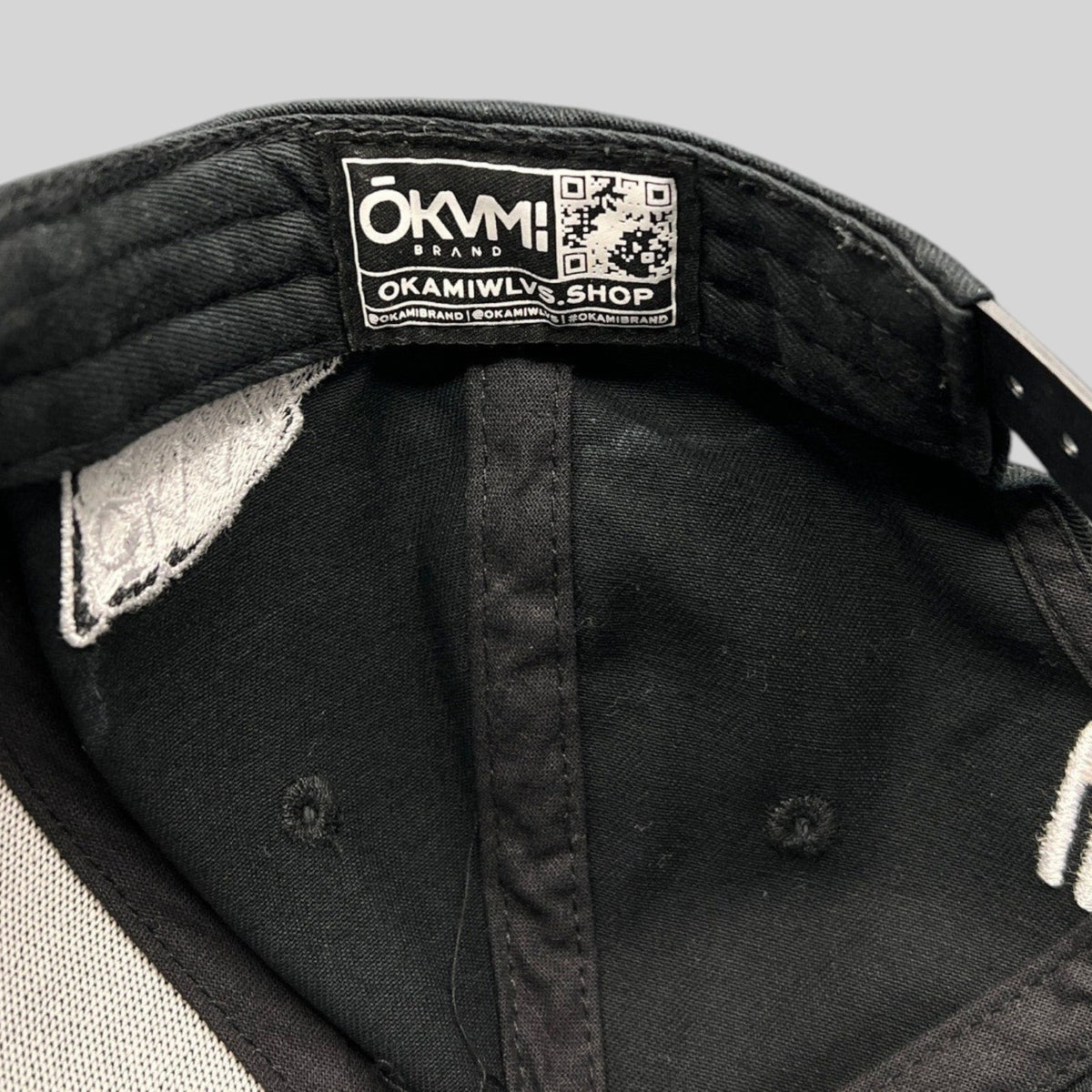 Raree Finds black Okami Brand strapback hat interior showing authentic branded label with QR code and taping