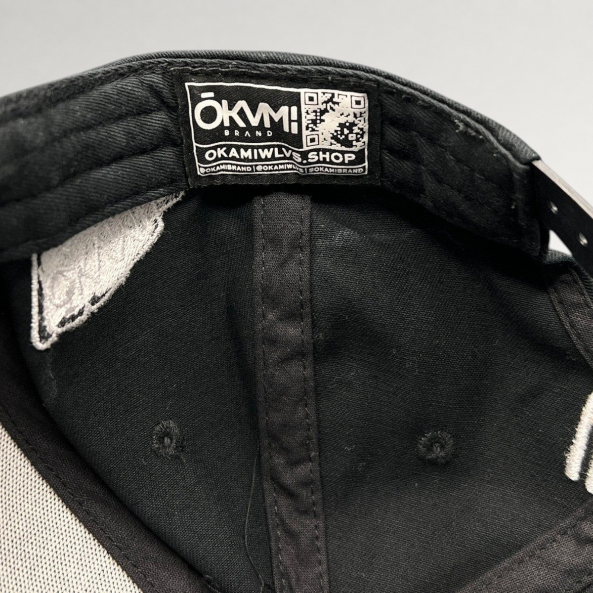 Raree Finds black Okami Brand strapback hat interior showing authentic branded label with QR code and taping