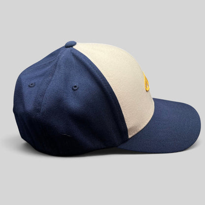 Raree Finds vintage O’Neill Flexfit surf cap with a white crown, navy panels, and gold wave logo embroidery.