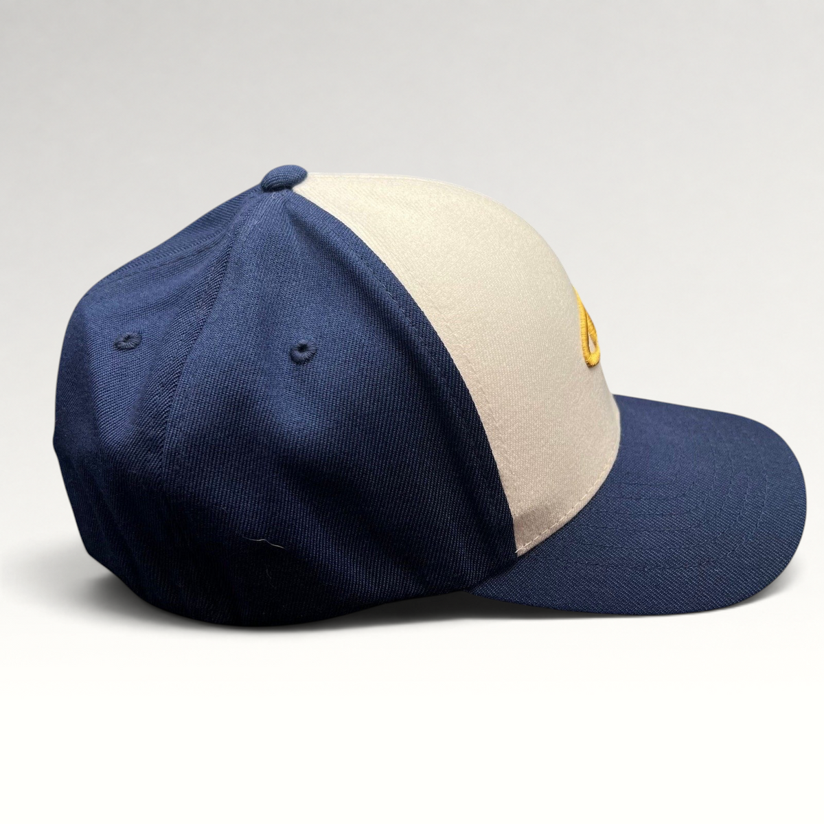 Raree Finds vintage O’Neill Flexfit surf cap with a white crown, navy panels, and gold wave logo embroidery.