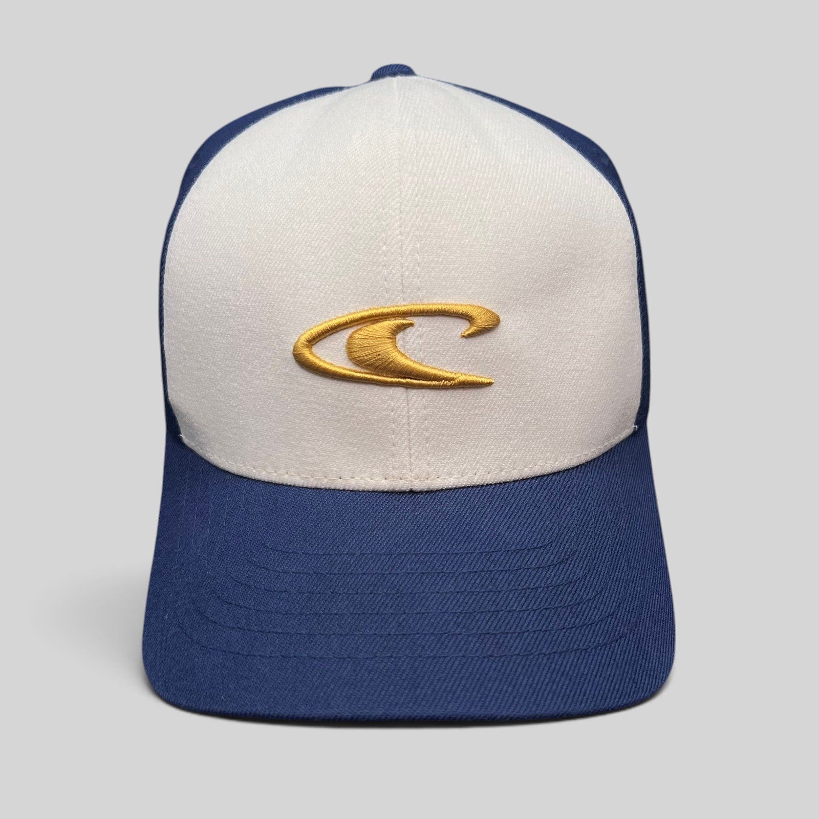 Raree Finds vintage O’Neill Flexfit surf cap with a white crown, navy bill, and gold embroidered wave logo.