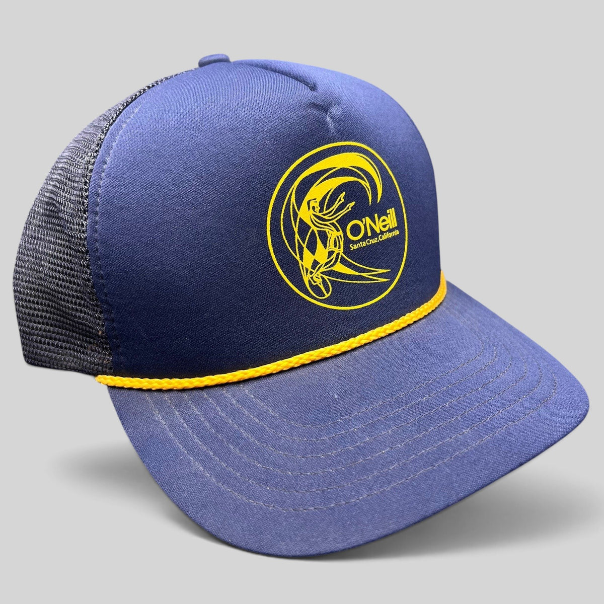 Raree Finds vintage O’Neill navy and yellow trucker hat with surf graphic, rope detail, and mesh back.