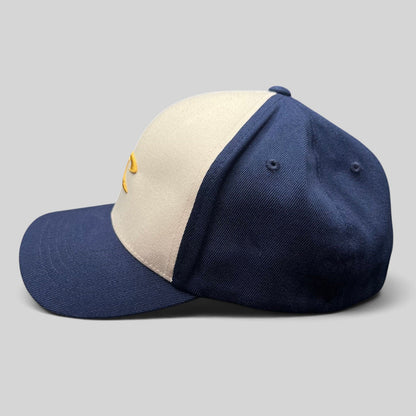 Raree Finds vintage O’Neill Flexfit surf cap with a white front panel, navy bill, and gold embroidered wave logo.