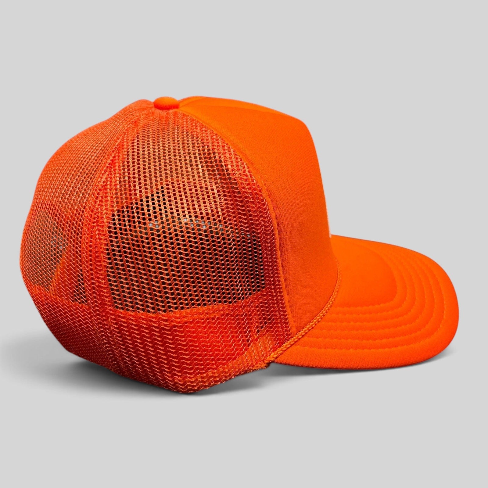 Raree Finds bright orange OTTO trucker hat with foam front and breathable mesh back panels, side profile view.