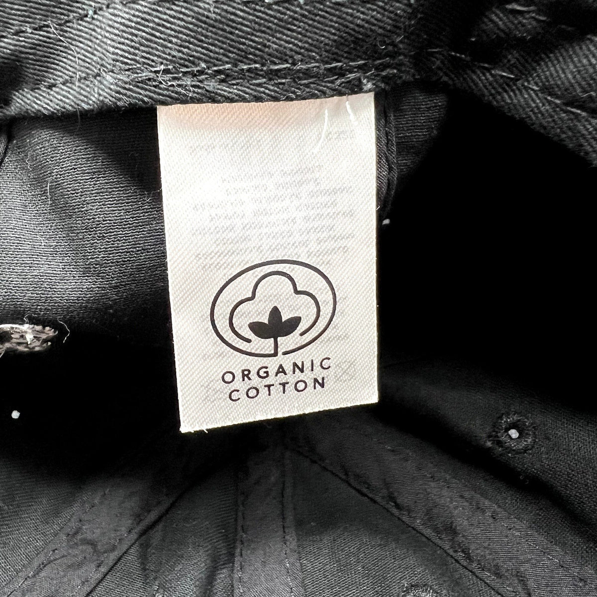 Raree Finds black organic cotton dad cap interior label showing the organic cotton certification logo
