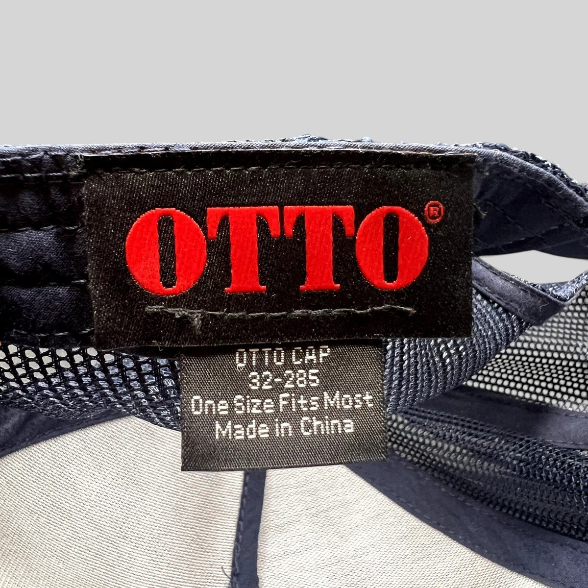 Raree Finds Otto trucker hat interior tag showing brand logo and manufacturing details on navy mesh fabric