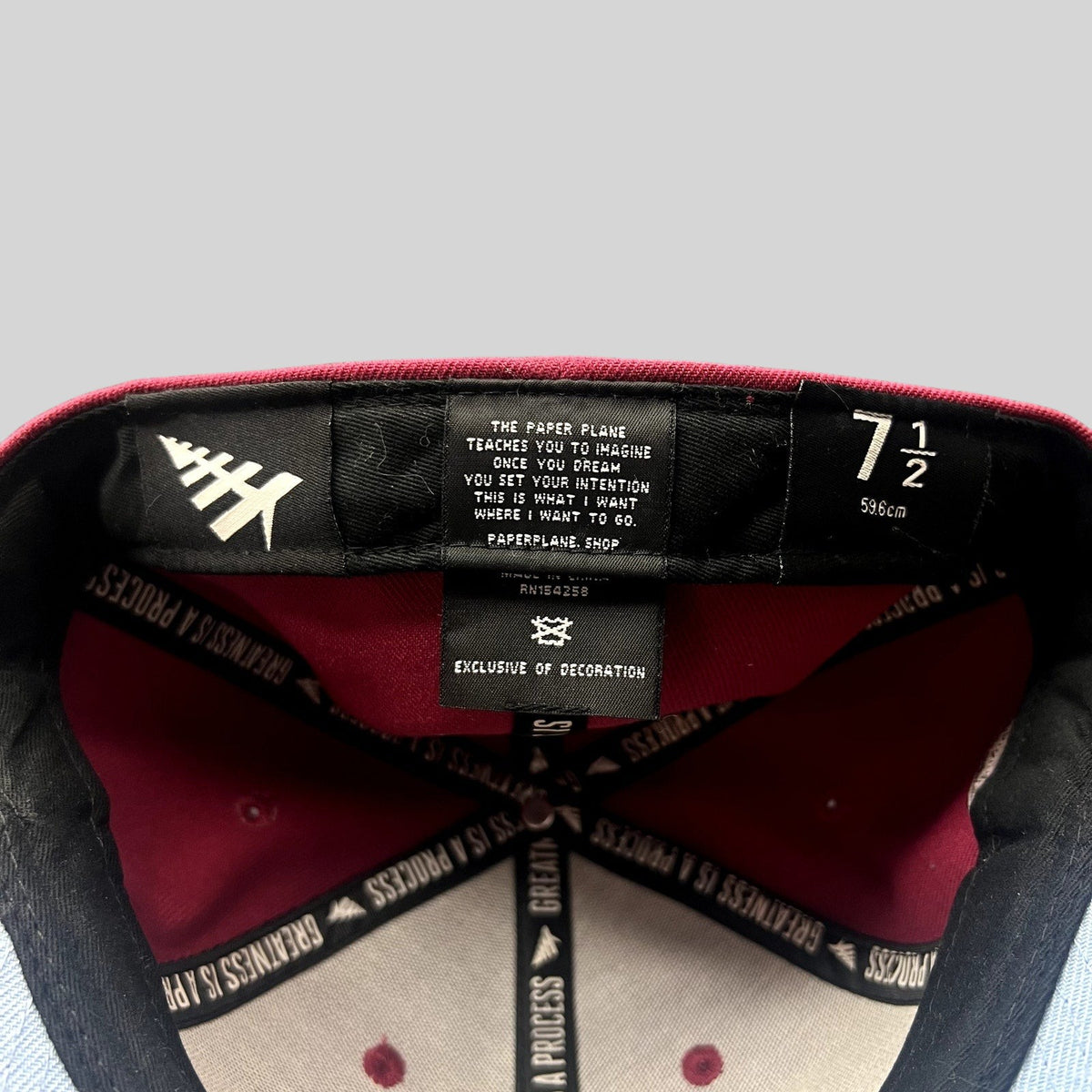 Raree Finds Paper Planes burgundy fitted hat interior showing size 7 1/2 tag and Greatness Is A Process taping