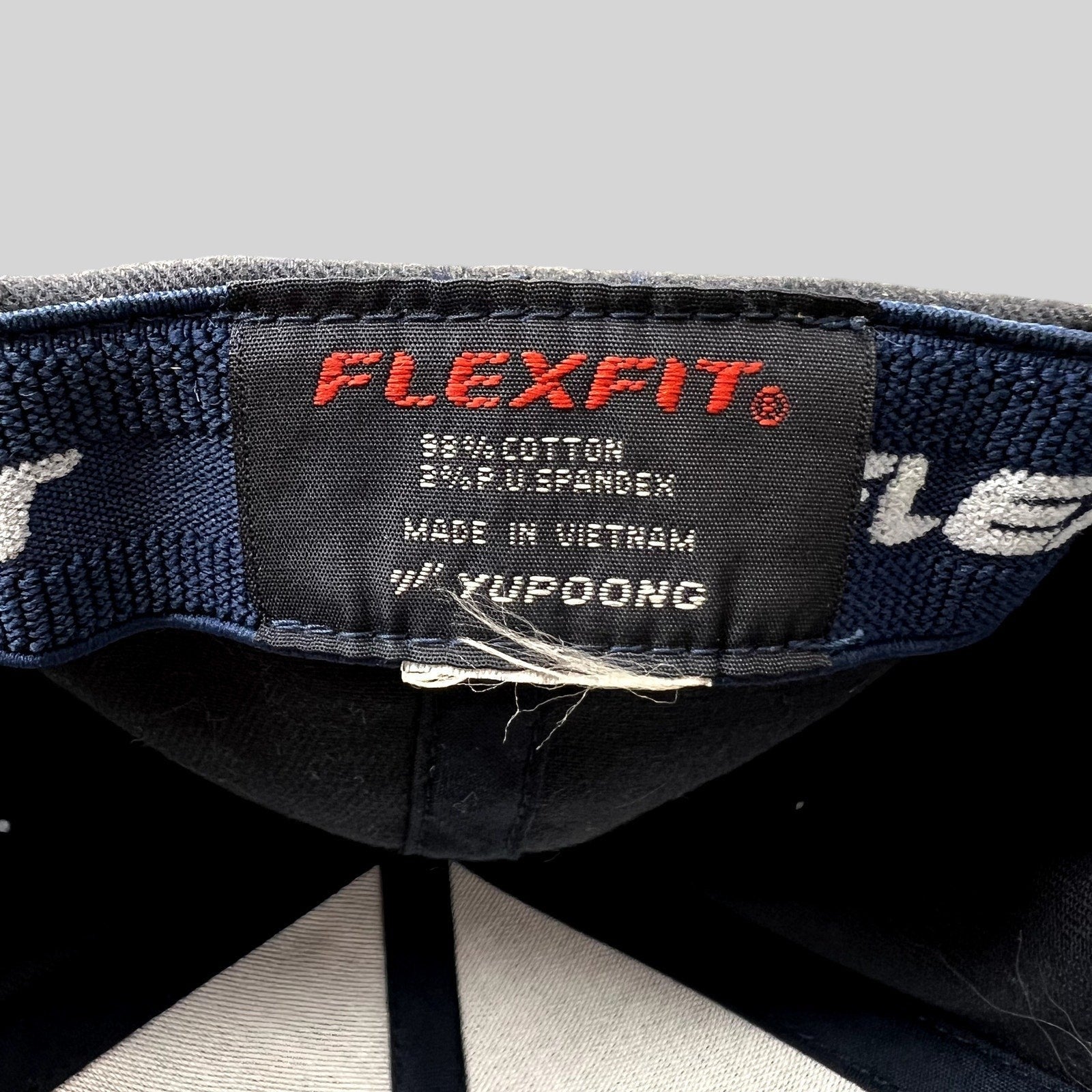 Raree Finds Porsche Woodland Hills hat interior tag showing Yupoong Flexfit branding and cotton spandex material