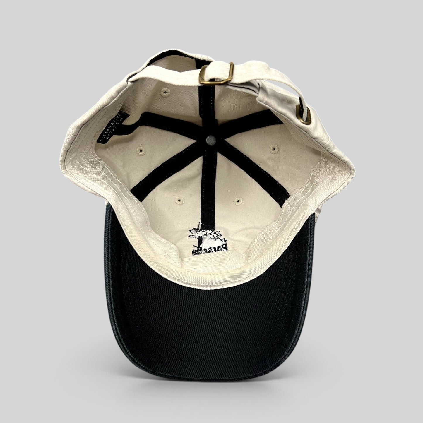 Raree Finds Porsche Driving Experience strapback hat in black and cream with brass hardware and interior logo detail.